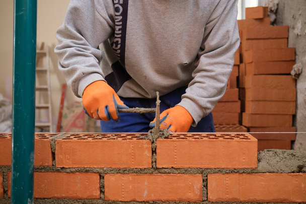 Trabalhador da construção civil a construir uma parede de tijolos. Assentamento de tijolos. Mason colocação de tijolos. - Foto, Imagem