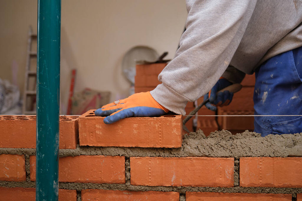 Trabalhador da construção civil a construir uma parede de tijolos. Assentamento de tijolos. Mason colocação de tijolos. - Foto, Imagem