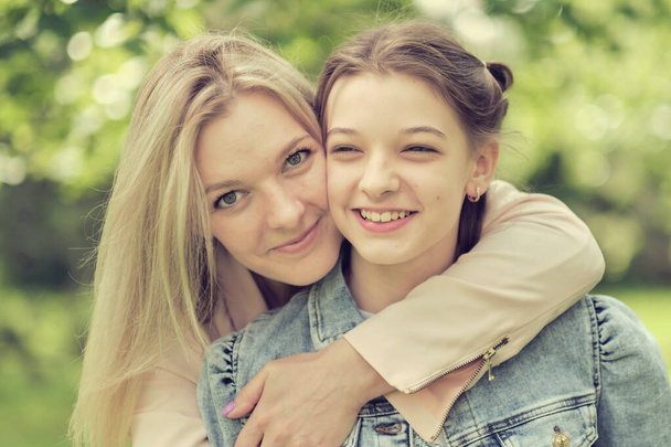 happy mother with her daughter hugging a teenager in the summer. Caring happy mother enjoy day with teenage girl child, laugh have fun. Mother giving her daughter advice. - Photo, image