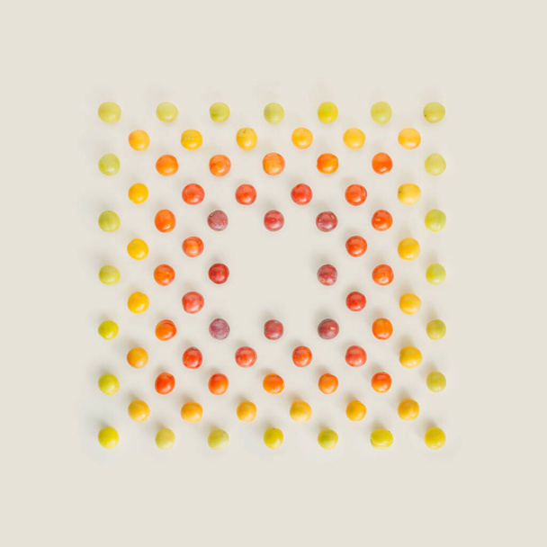 淡い緑、黄色、オレンジ、大胆な赤の野生のプラムで作られた正方形のノートカードの形は、パステルベージュの背景に隔離されています。自然からインスピレーションを受けたカラフルな夏のフルーツパターンコピースペース。極小平面. - 写真・画像