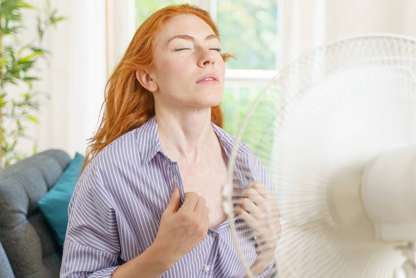 Eine Frau versucht sich zu Hause mit einem Ventilator abzukühlen - Foto, Bild