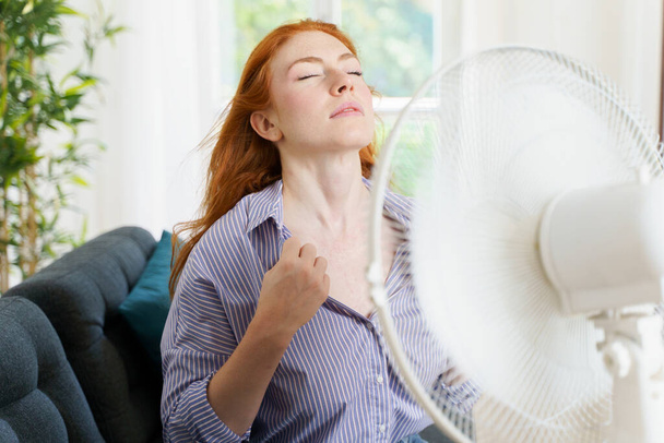 Eine Frau versucht sich zu Hause mit einem Ventilator abzukühlen - Foto, Bild