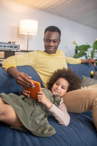 Dark-skinned dad with little daughter looking at tablet - Photo, Image