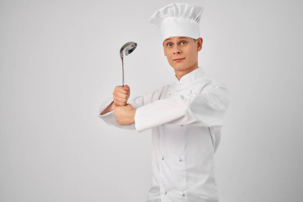Ένας άντρας με στολή σεφ μαγειρικά σκεύη δουλεύει σε εστιατόριο. - Φωτογραφία, εικόνα