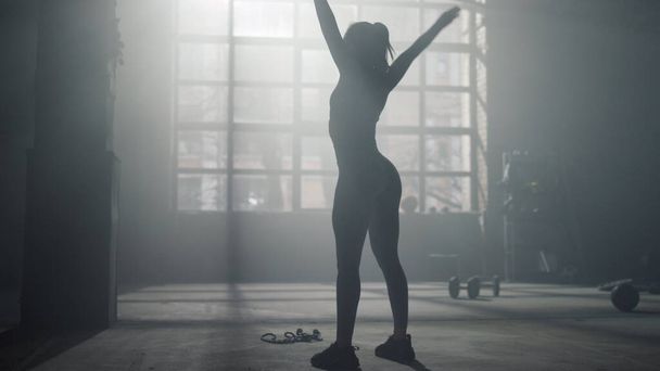 Een vrouw die stretchoefeningen doet in een sportclub. Vrouwelijke atleet opwarming handen  - Foto, afbeelding