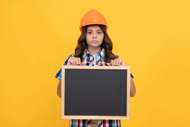 серьезный ребенок в шлеме, представляющий школьную доску с рекламой, копировальным пространством, школой - Фото, изображение