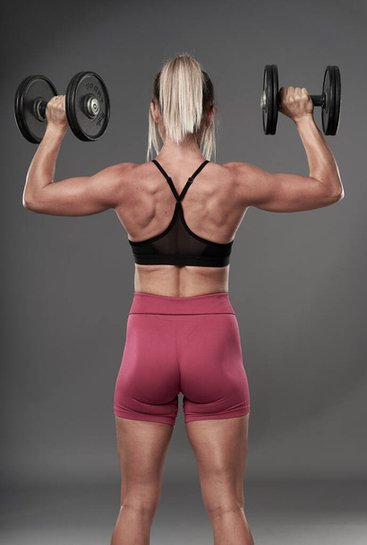 Fit bodybuilder woman doing fitness exercises on gray background, studio shot - Fotó, kép