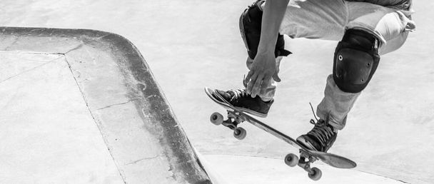 A grayscale action shot of skateboarder's feet while skating - Фото, изображение