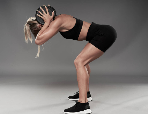 Fit bodybuilder woman doing fitness exercises on gray background, studio shot - Foto, Imagem