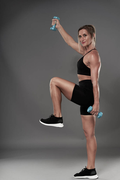Fit bodybuilder woman doing fitness exercises on gray background, studio shot - Fotoğraf, Görsel