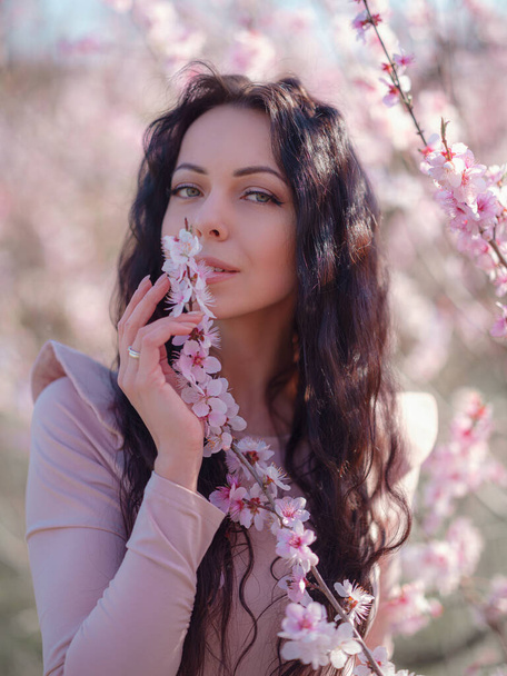 Çiçek açan kiraz ağacının yanında güzel bir genç kadın. İnanılmaz hafif bir portre. - Fotoğraf, Görsel