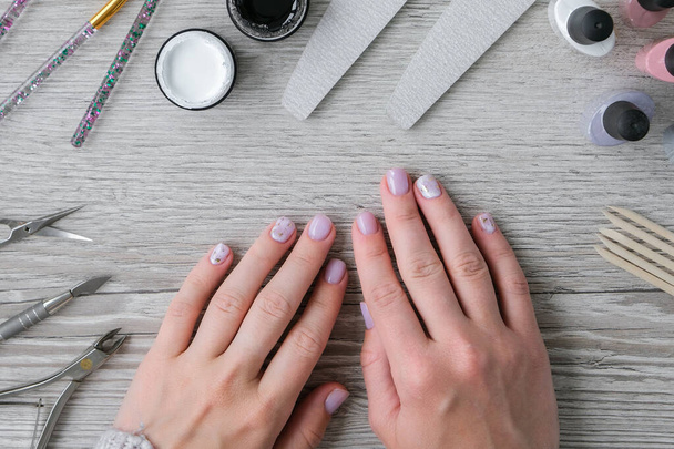 Modern female nude design manicure. Nail care, Self care. Do manicure by yourself while staying at home. Female hands and manicure tools. Spa salon. Professional Hardware Manicure. Procedure for the preparation of nails. Cuticle Pusher Remover. Nail  - Zdjęcie, obraz