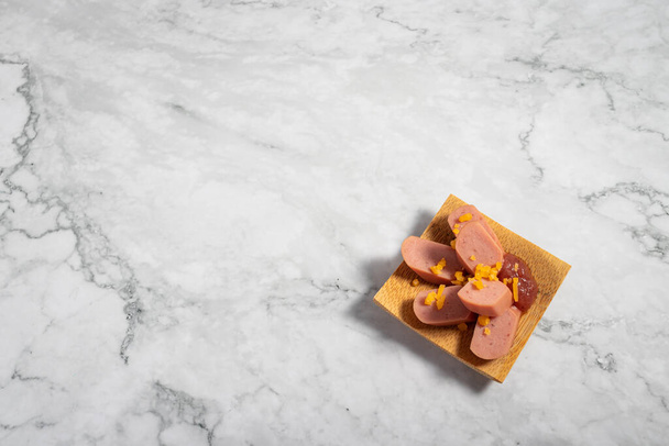 A delicious appetizer on a small wooden plate on a marble texture table - Fotoğraf, Görsel