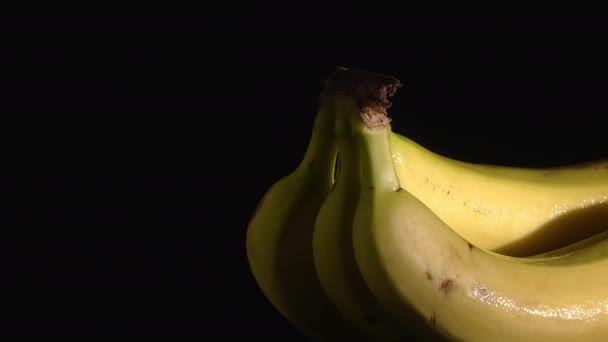 Крупним планом знімок мокрих бананів, що обертаються на тумбочці з чорним тлом
. - Кадри, відео