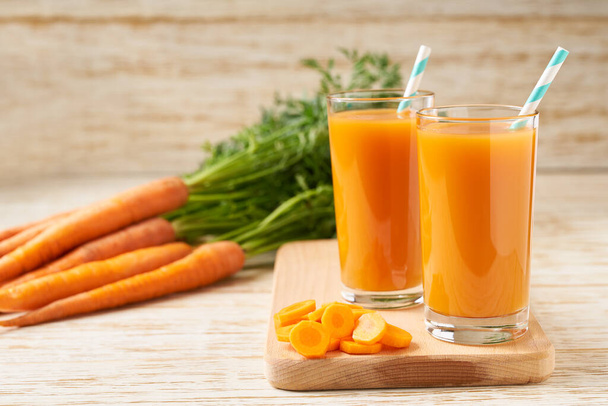 Vasos de jugo de zanahoria con verduras en una mesa de madera. Zanahoria fresca y jugo (batidos). - Foto, imagen