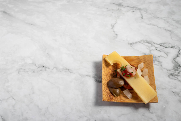 A delicious appetizer on a small wooden plate on a marble texture table - 写真・画像