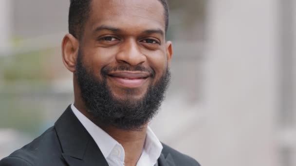 Szoros portré mosolygós, boldog, szakállas afro-amerikai fekete férfiről öltönyben. Fiatal felnőtt sikeres férfi üzletember vállalkozó vagy magabiztos millenniumi diák felemeli a kezét mutató ok gesztus - Felvétel, videó