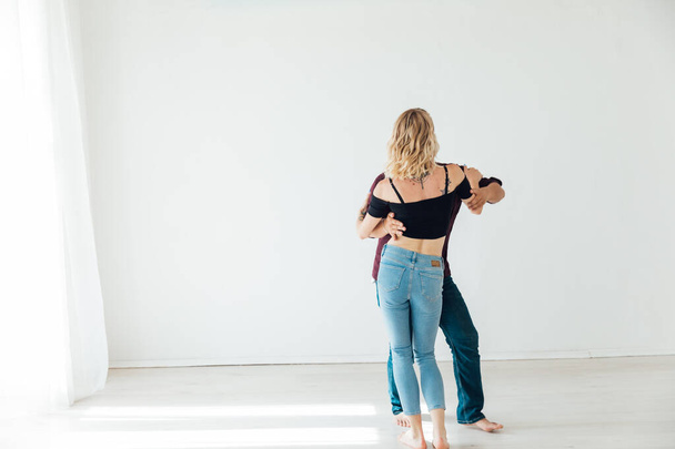 hermoso hombre y mujer bailando juntos a la música en una habitación blanca - Foto, Imagen