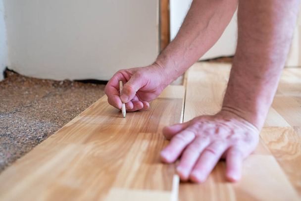 Caucasian man installing wood parquet board during flooring work - Φωτογραφία, εικόνα