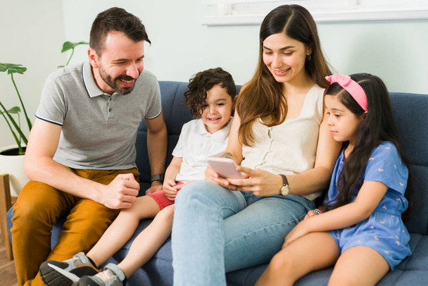 Ready to make a family video call. Happy young mother showing an online video on her smartphone to her husband and little kids - Фото, изображение
