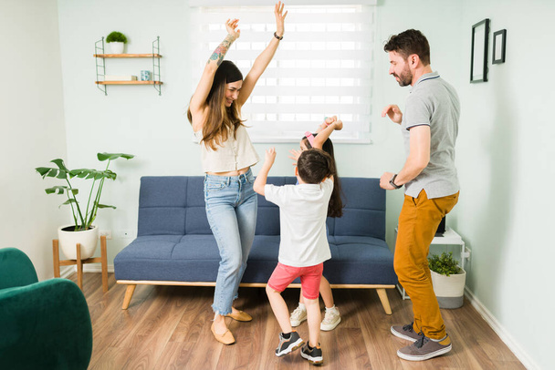 Mãe atraente alegre rindo enquanto dança com seus filhos bonitos e marido. Linda família de quatro pessoas ouvindo música e tocando  - Foto, Imagem