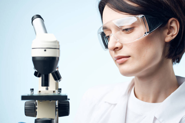 female laboratory assistant looking at a microscope technology research - Valokuva, kuva