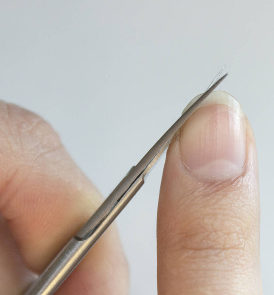 A person cuts his nails with small scissors. Men's manicure. A man cuts off a large overgrown nail - Fotoğraf, Görsel