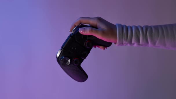 Hand mit grauem Gamepad auf violettem Hintergrund. Bomerangs vertikales Video. - Filmmaterial, Video