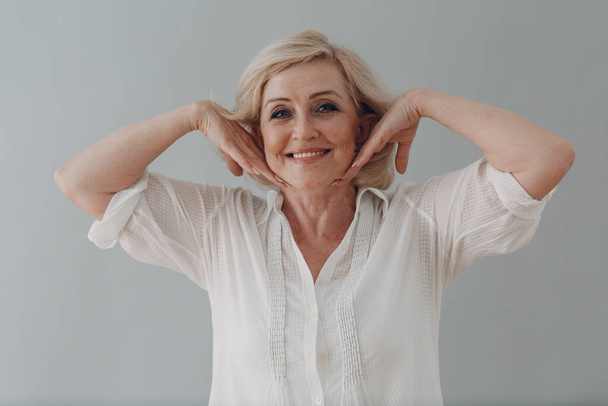 Elderly caucasian old aged woman gray haired portrait doing facebuilding yoga face gymnastics yoga self massage. - Photo, Image