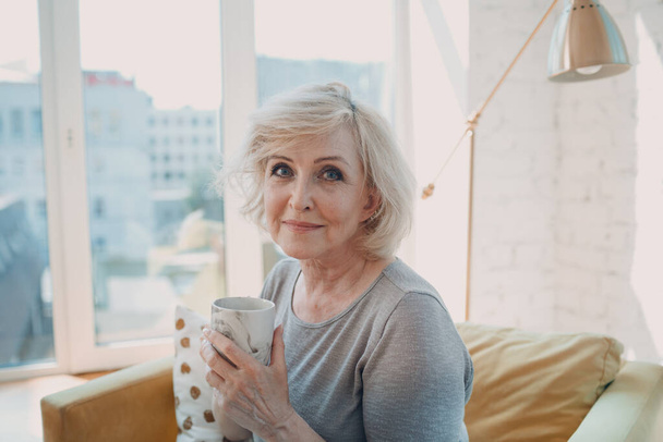 w podeszłym wieku biały stary kobieta cieszy się popołudniową herbatą w domu. - Zdjęcie, obraz