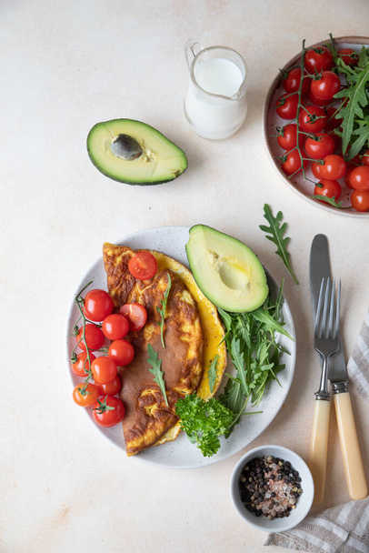 Omelette served with avocado, cherry tomatoes and arugula on ceramic plate. Healthy and tasty keto breakfast or brunch. Ketogenic diet. - Zdjęcie, obraz