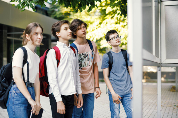 Koulukaverit katselevat aikataulua koulun edessä - Valokuva, kuva