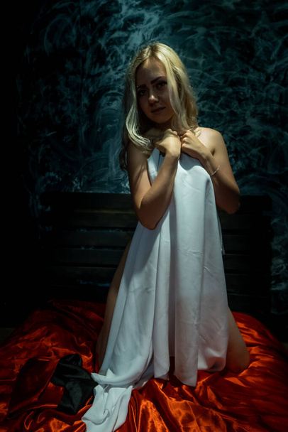 Topless blonde, covered with a white cloth on a black background - Фото, зображення