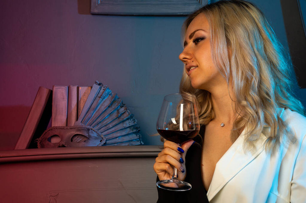 near a piano a beautiful girl in a black dress, a glass of wine - Photo, Image