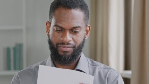 Feliz biracial preto jovem adulto do sexo masculino recebendo correio carta, aviso de papel de aprovação de empréstimo bancário, aumento de salário, promoção. Um africano a ler boas notícias, a regozijar a vitória. Boas novas inesperadas - Filmagem, Vídeo
