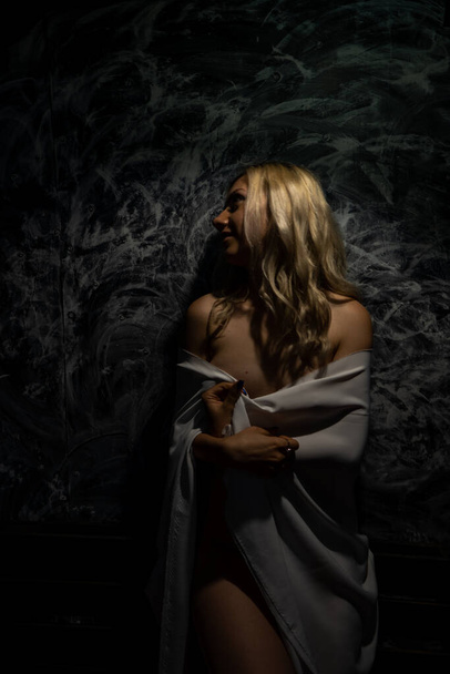 Topless blonde, covered with a white cloth on a black background - Foto, Imagem