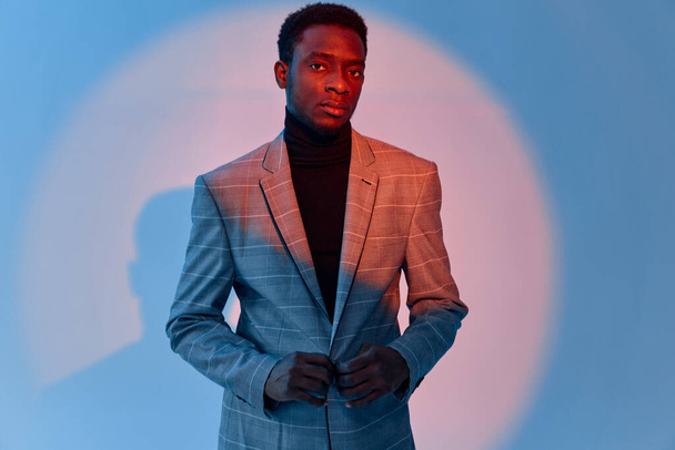 Mann afrikanisches Aussehen graue Jacke Selbstvertrauen Neon Hintergrund - Foto, Bild