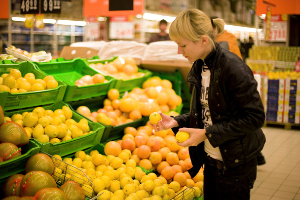 The woman buys lemons (Focus on hands) - Foto, afbeelding