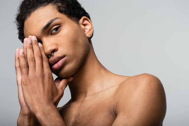 african american guy posing with hands near face while looking at camera isolated on grey, beauty concept - Foto, Imagen