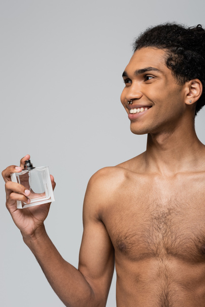 shirtless and happy african american man applying perfume isolated on grey - Foto, immagini