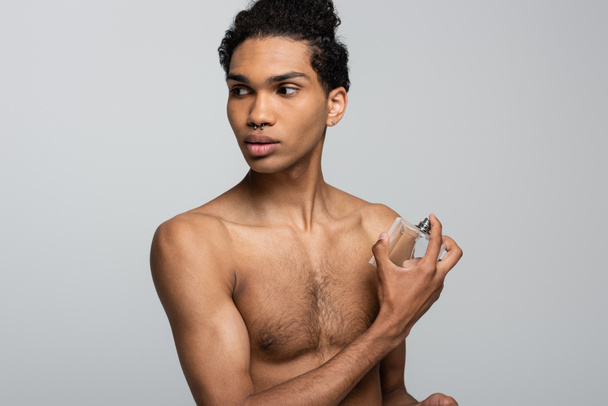 bez koszulki Afrykański Amerykanin stosujący perfumy odwracając wzrok na szarym - Zdjęcie, obraz