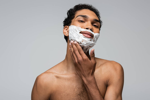 african american guy looking at camera while applying shaving foam isolated on grey - Fotoğraf, Görsel