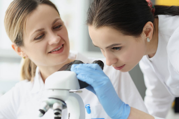 Female scientists chemists looking through microscope in laboratory - Foto, Imagen