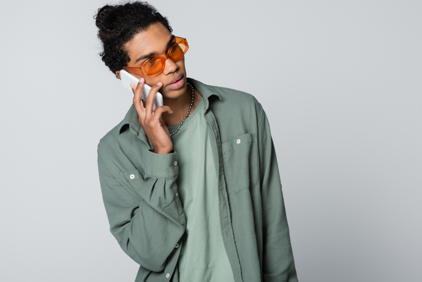 african american guy in shirt and eyeglasses talking on smartphone isolated on grey - Fotografie, Obrázek
