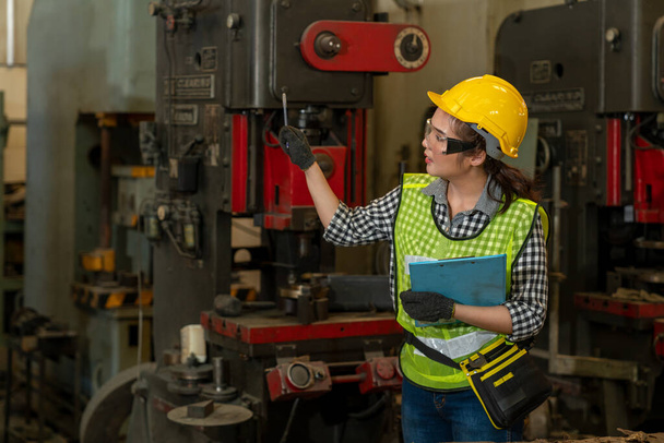 Asian female technician engineer holding clipboard while checking  machines in the factory on business day. Confident worker wearing particulate respirator mask with hard hat. Industrial manufacturing - Фото, зображення