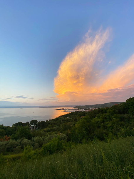 Scenic view to the amazing red sunset at the Adriatic sea, coast in Slovenia at summer. View to green hills and olive trees. Natural backgrounds.  - Photo, Image