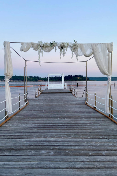 Witte trouwboog prachtig versierd met bloemen op de brug, pier. Adriatische kust en zee in Slovenië. Vakantie, bruiloft en viering concept.  - Foto, afbeelding