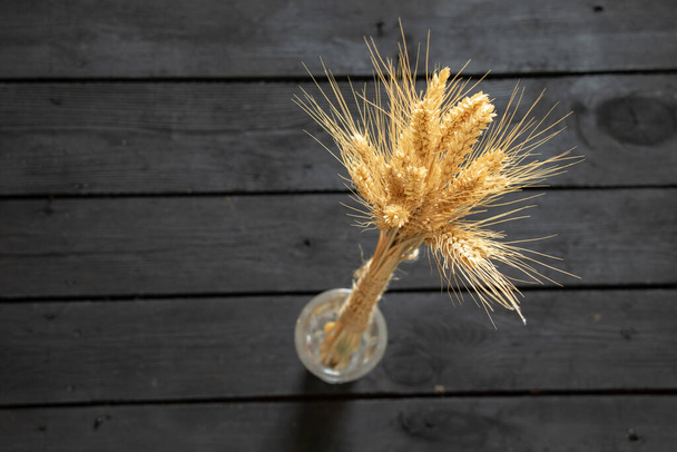 spighe di grano secco in un mazzo su un tavolo di legno nero, posto di grano per testo - Foto, immagini
