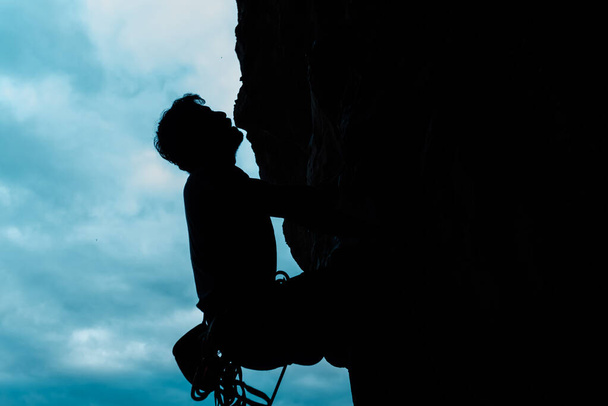 silhouet van klimmer die een berg beklimt. - Foto, afbeelding