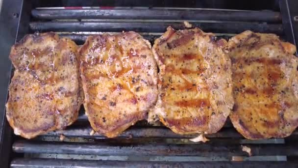 Grigliare bistecche di maiale. Deliziose succose bistecche di carne che cucinano sulla griglia.  - Filmati, video